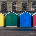 Four beach huts, each painted in the four primary colours, of yellow, green, blue and red.