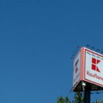 a red and white sign and some trees and a blue sky