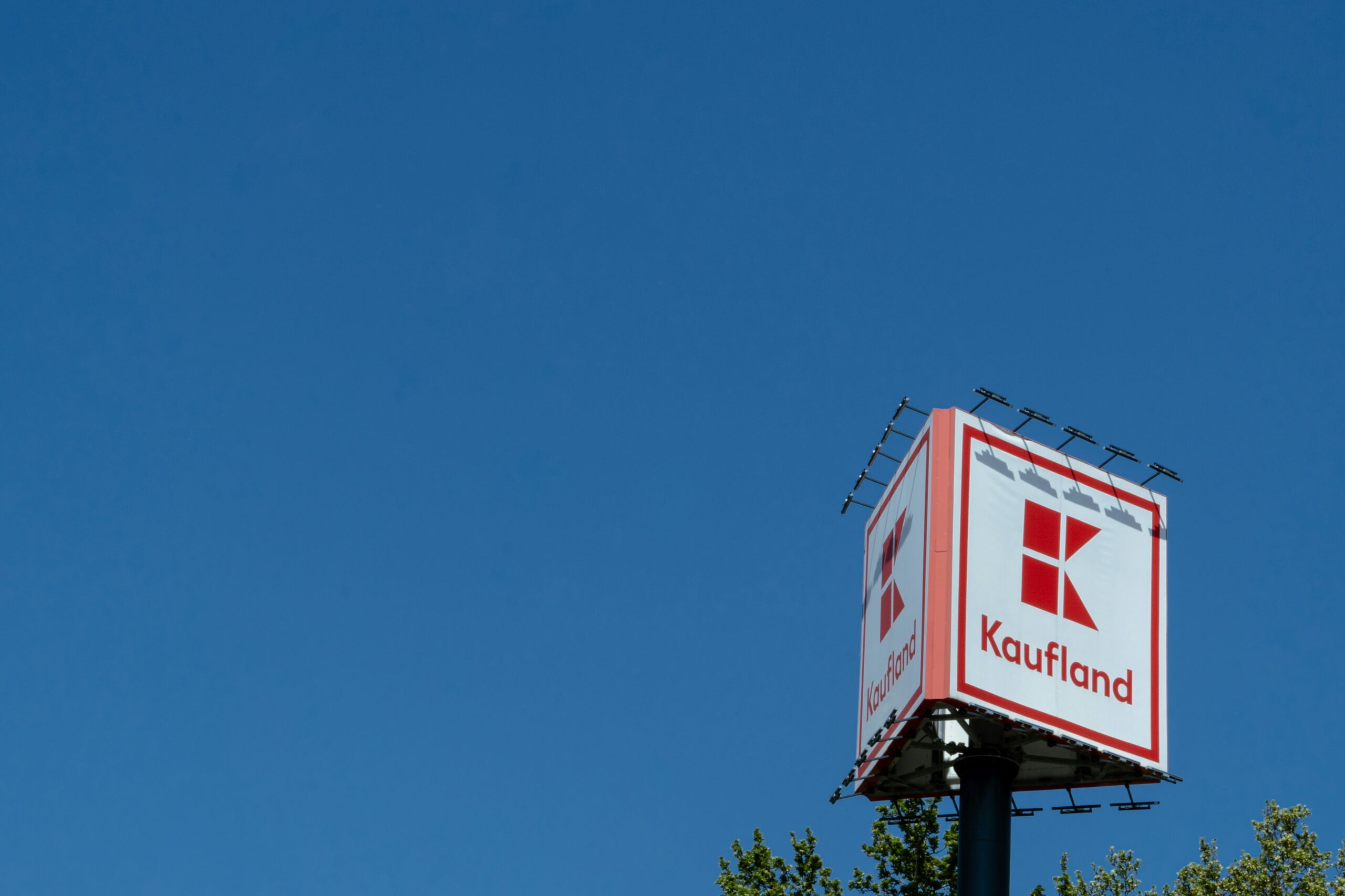 a red and white sign and some trees and a blue sky